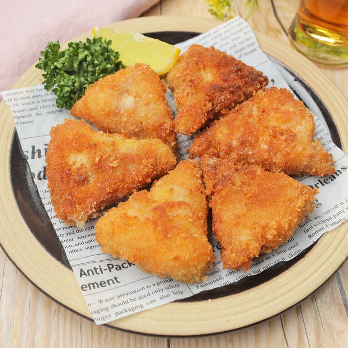 皿に盛られた料理とレモン。新聞紙が敷かれている。