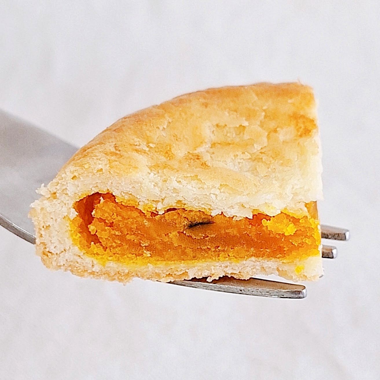 フォークに刺さったかぼちゃのフィリングのある一切れのパイ。