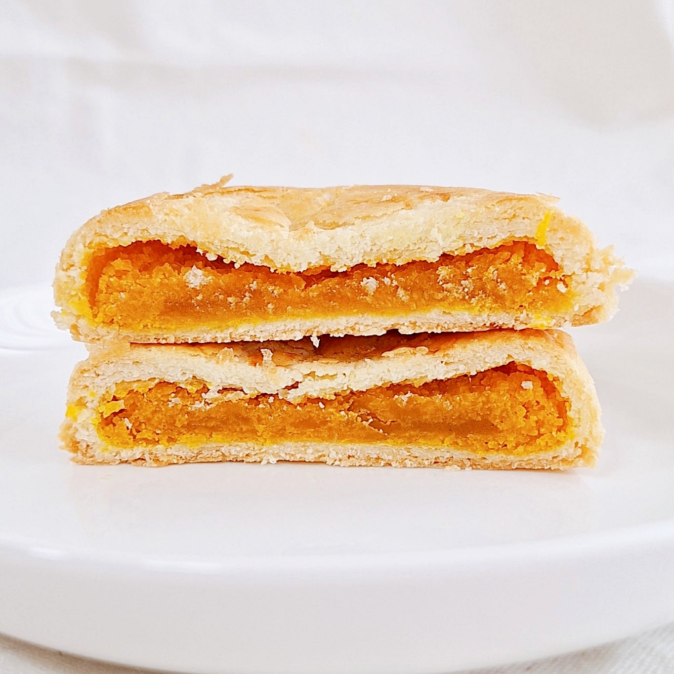 皿の上のクッキーが半分に割れて、オレンジ色のフィリングが見えている。