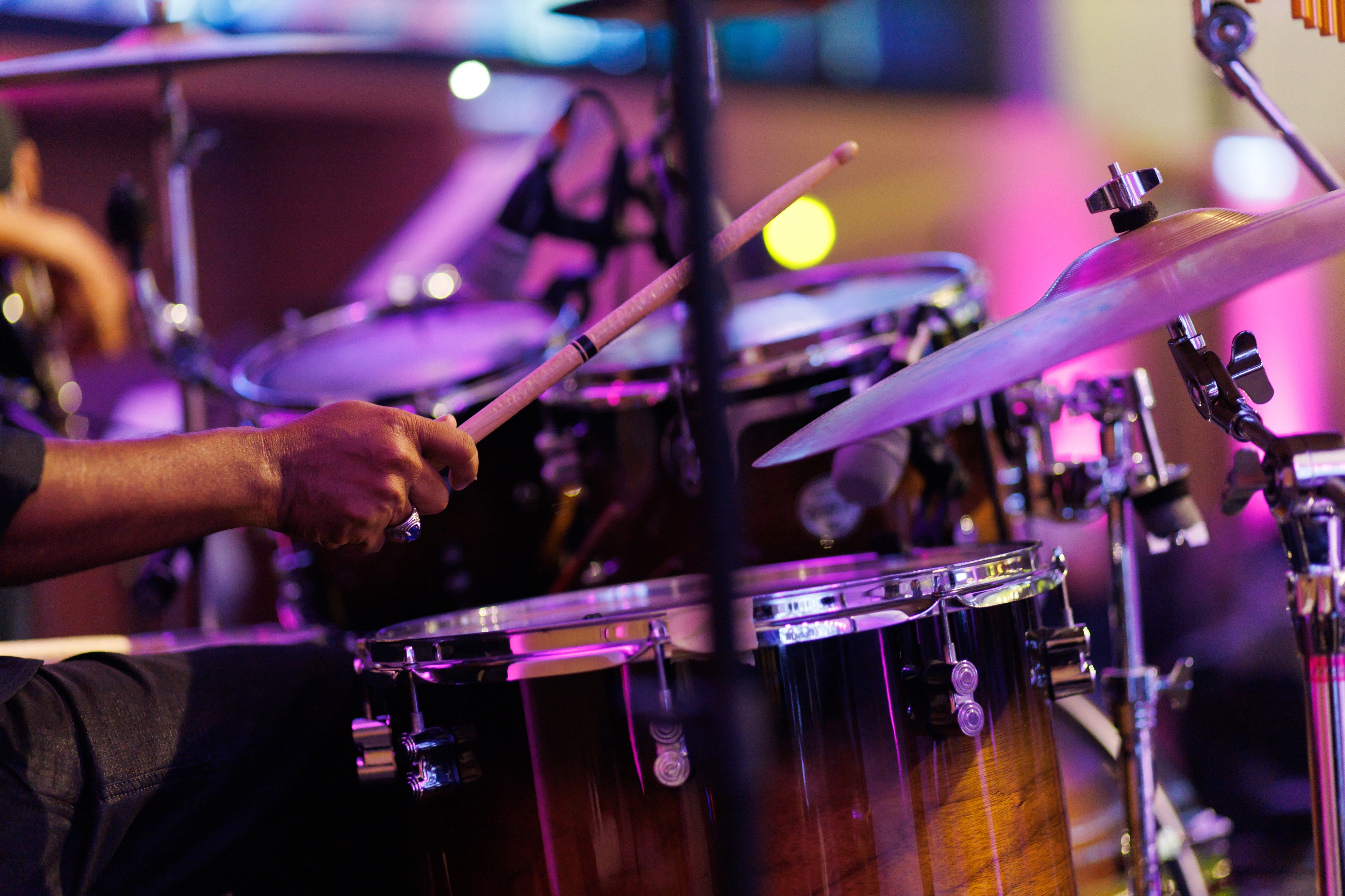 A drummer plays a drum set passionately on stage, capturing the rhythm and energy of the performance