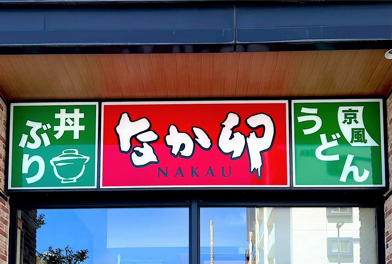 建物の入り口上に「なか卯」と書かれた看板。丼物や京風うどんのメニューを示している。