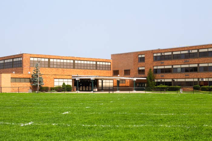 A large brick school building with neatly maintained lawns in front, indicating an educational setting