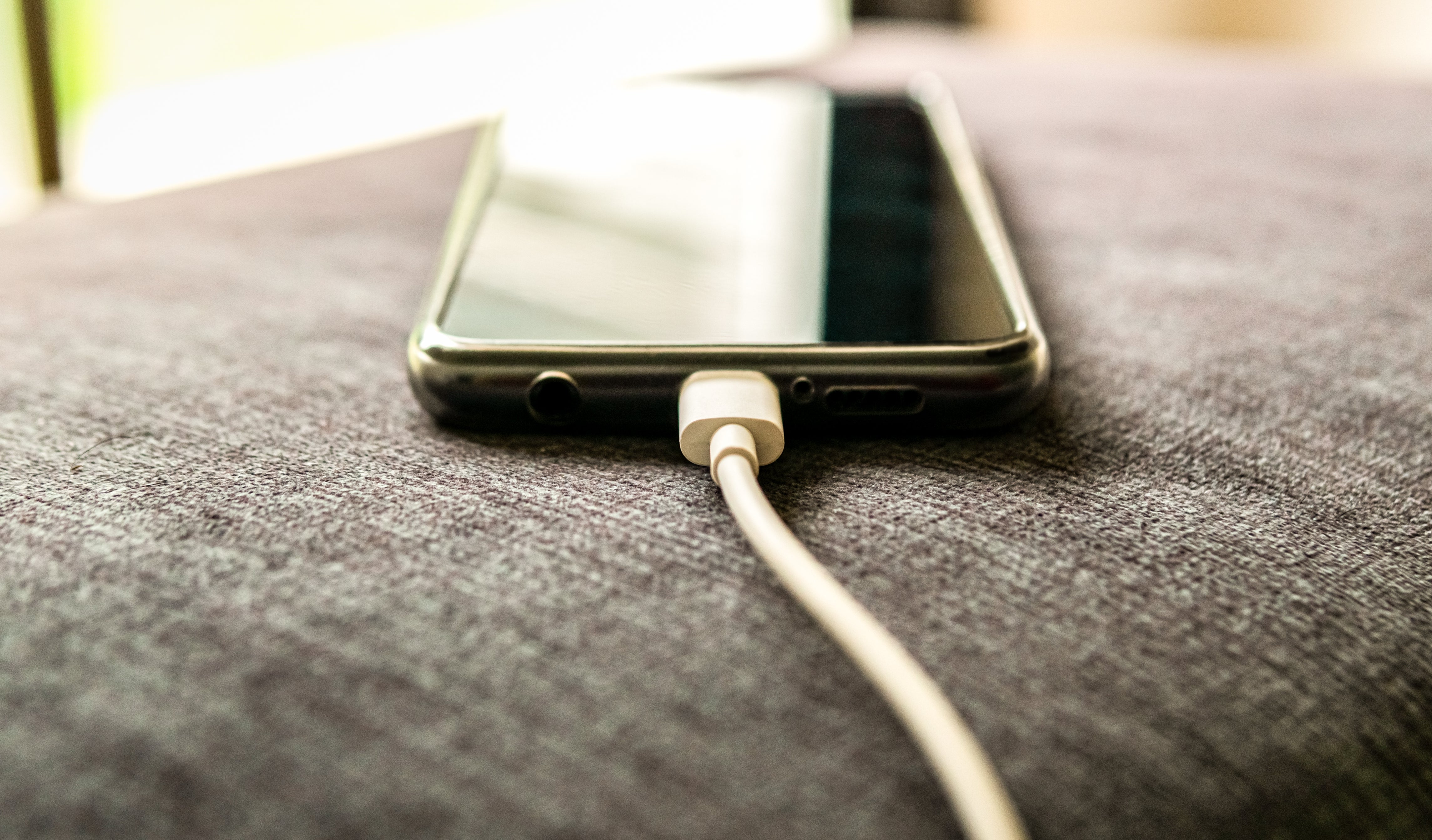 Smartphone charging on a fabric surface near a window