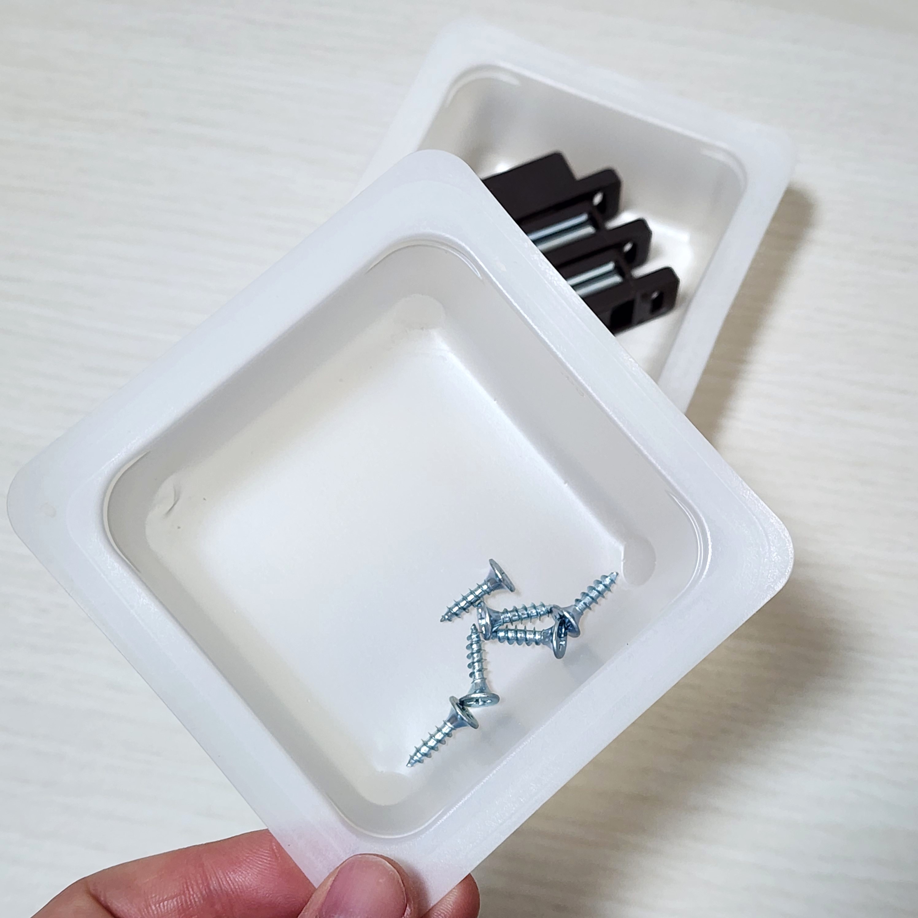 小さなトレーにネジと金属部品が収まっている様子を示しています。