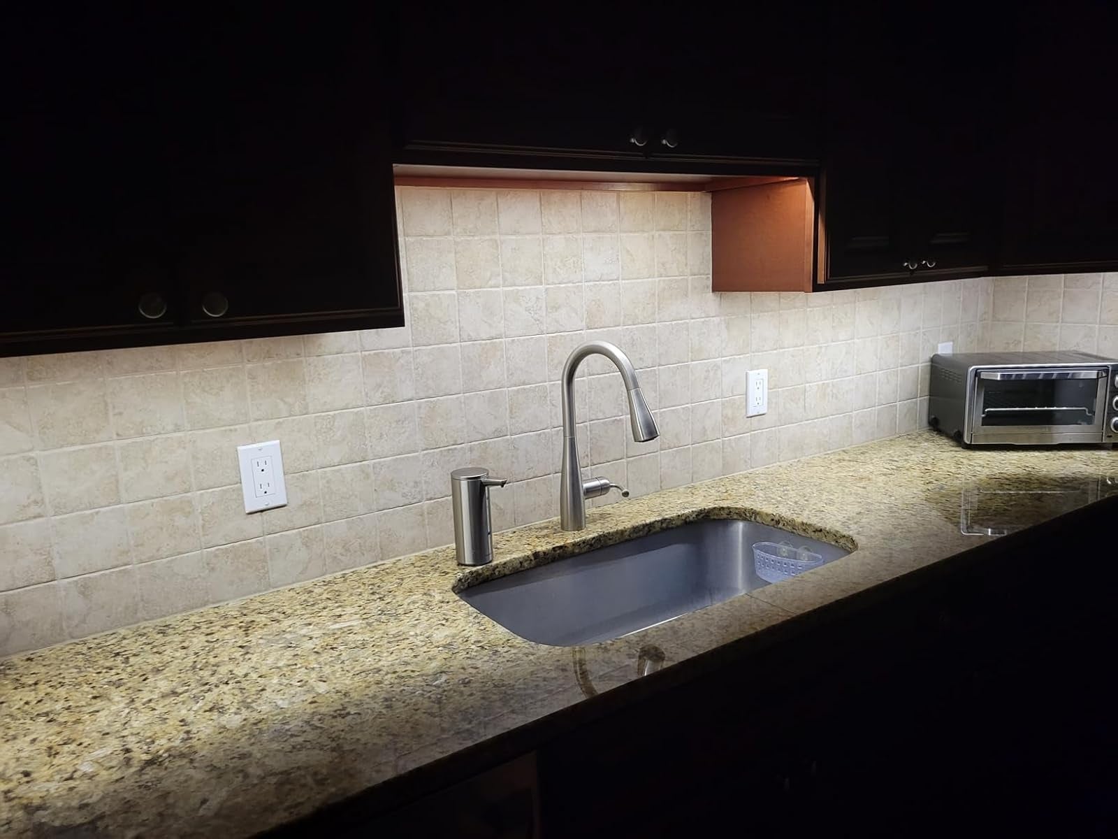Modern room  antagonistic  with granite surface, under-cabinet lighting, stainless alloy  sink, and a tiny  toaster oven