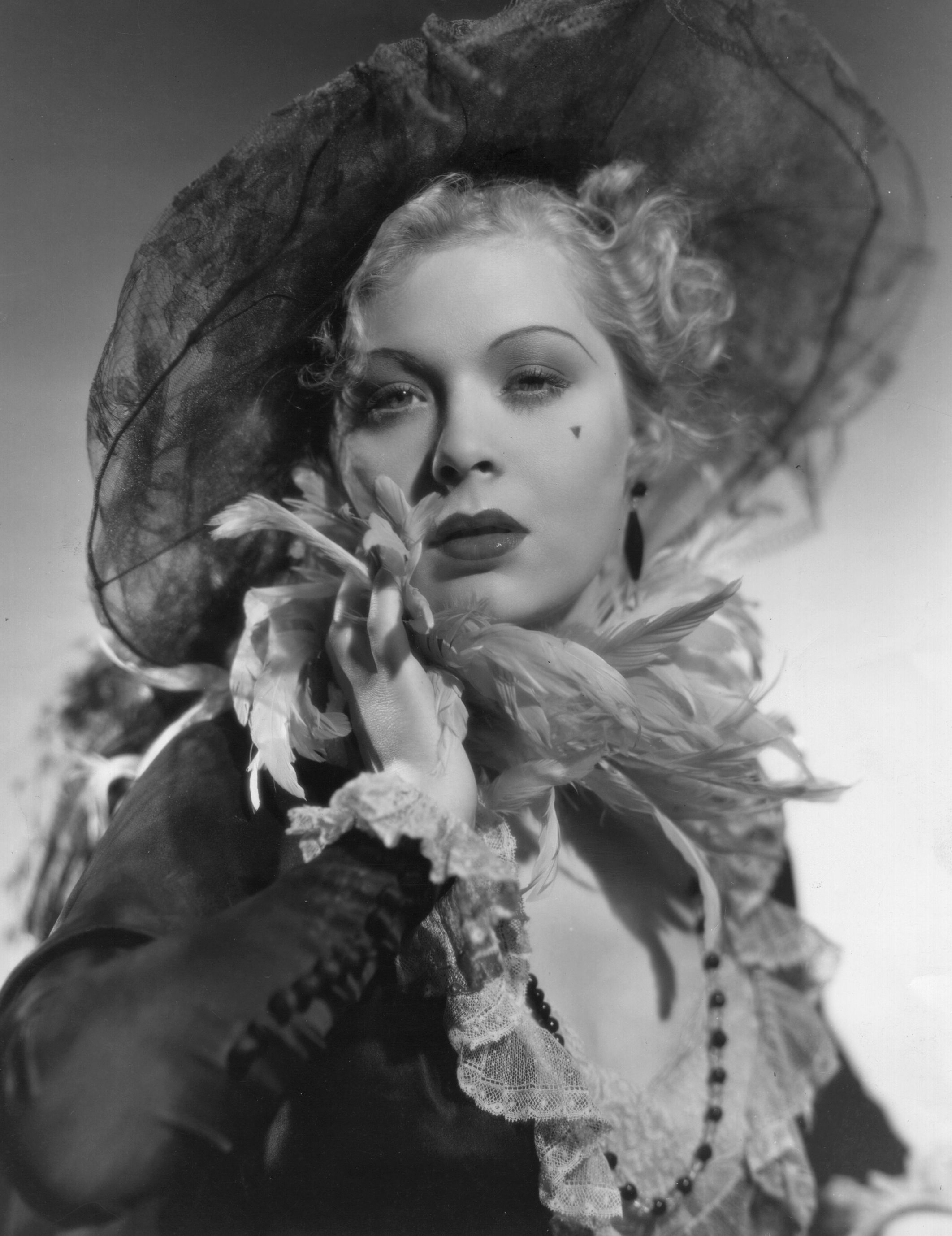 Vintage-style portrait of an actress wearing an elegant wide-brimmed hat, lace dress, and feathered accessory, exuding classic Hollywood glamor
