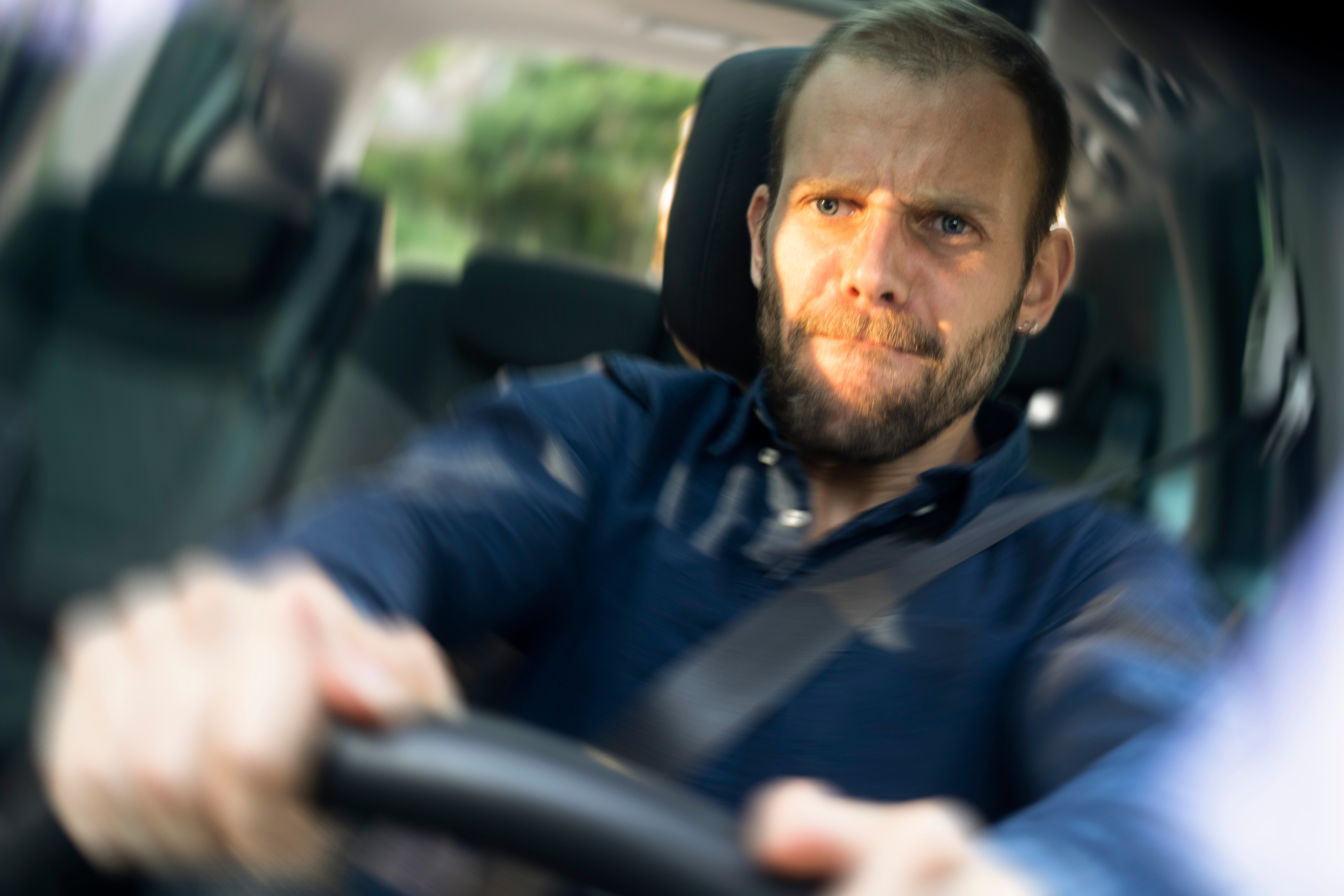 Man driving a car, looking focused and determined, gripping the steering wheel tightly