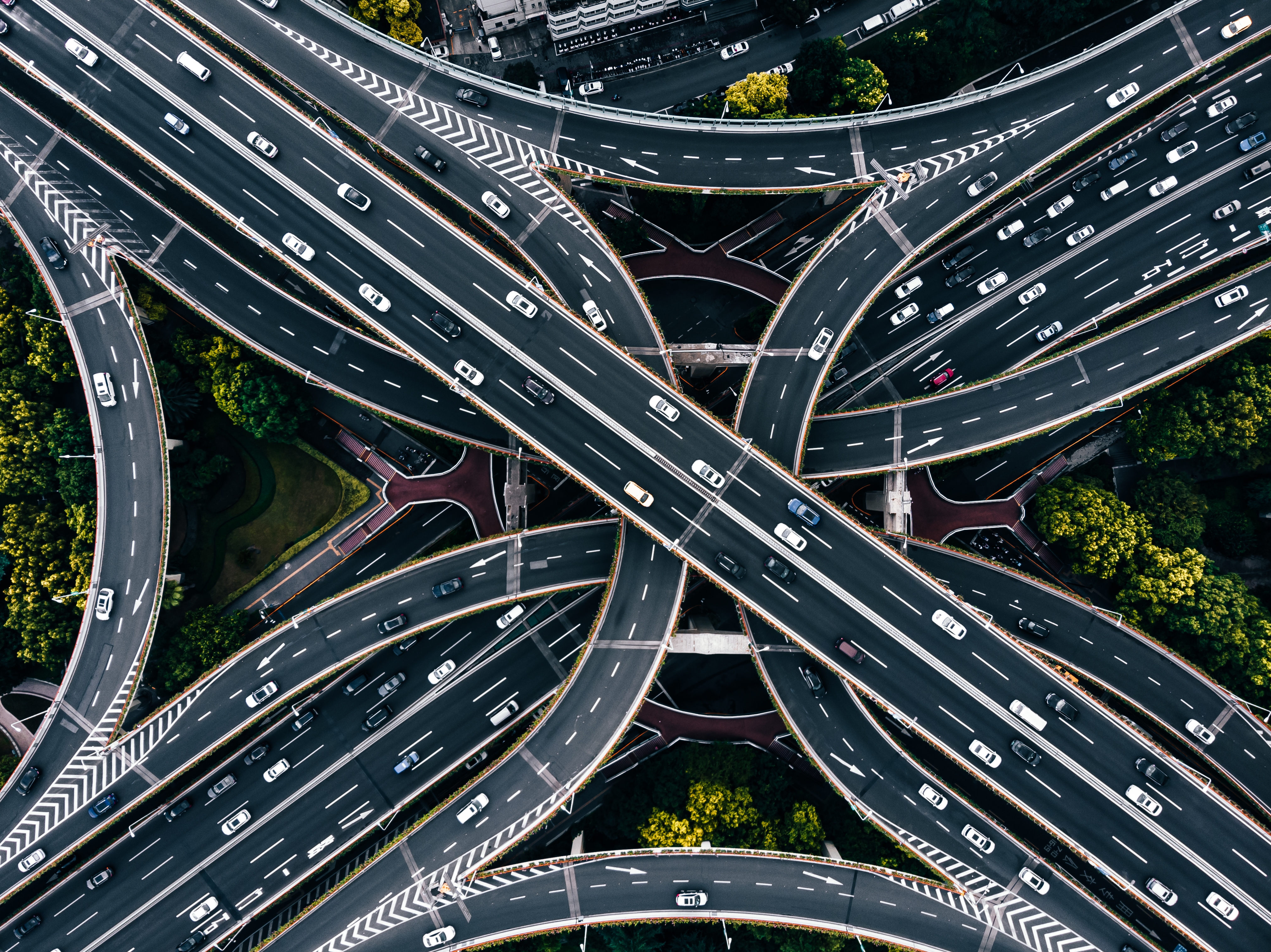 Aerial view of a complex, multi-layered highway interchange with cars, surrounded by greenery