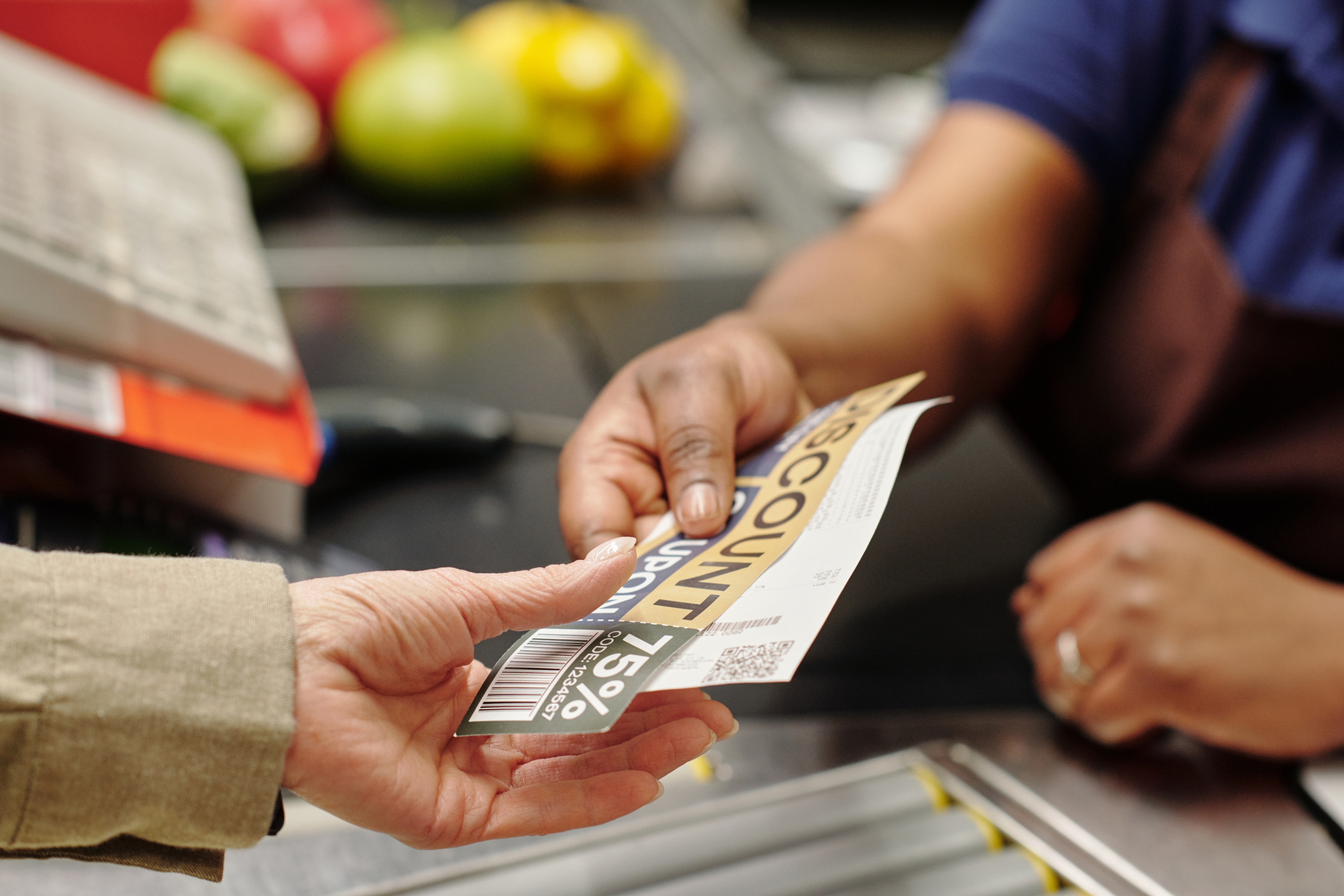 Person handing a discount coupon to a cashier at a checkout counter