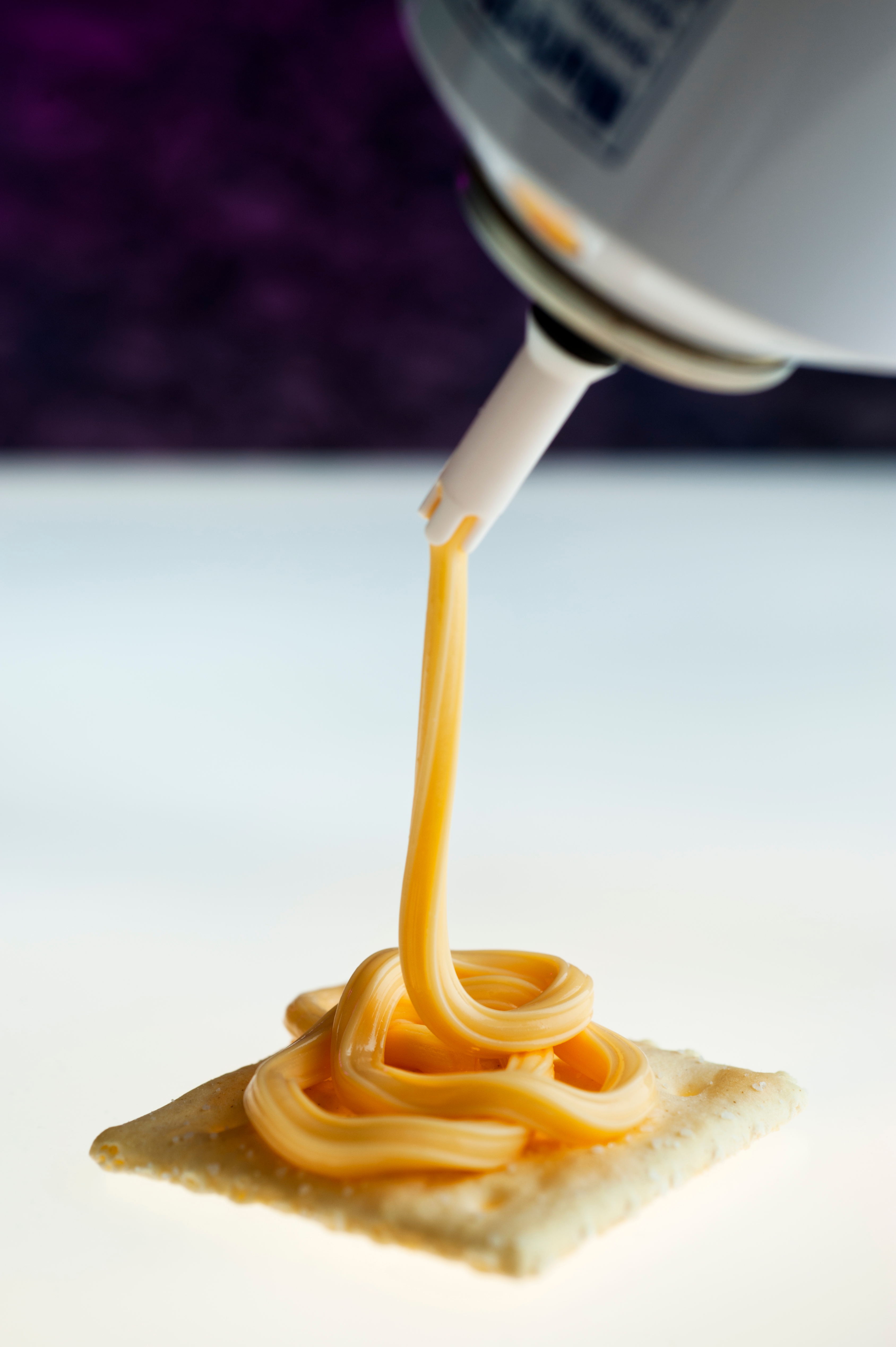 Cheese being dispensed onto a cracker from an aerosol can