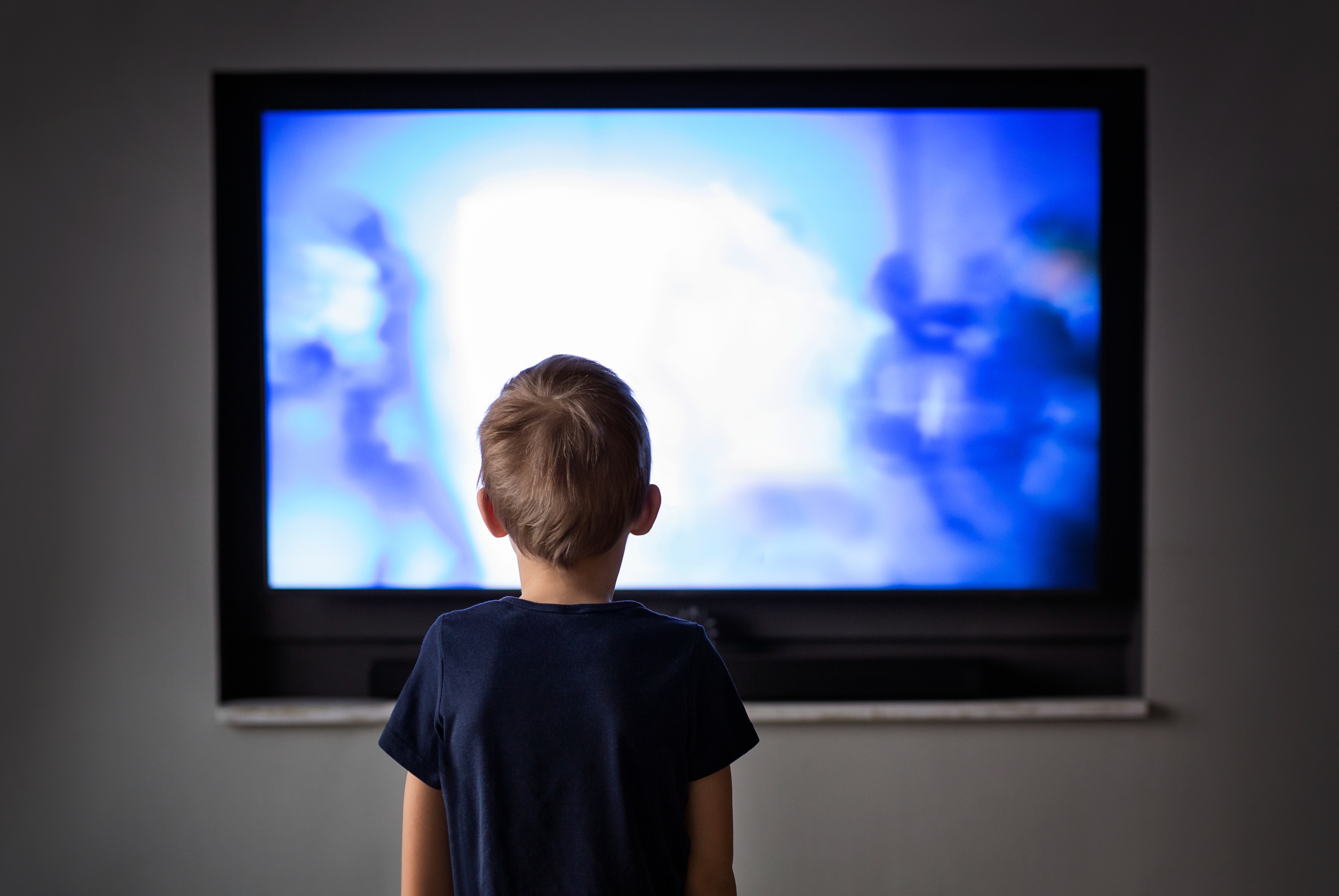 Child watching TV screen with blurred action scene displayed