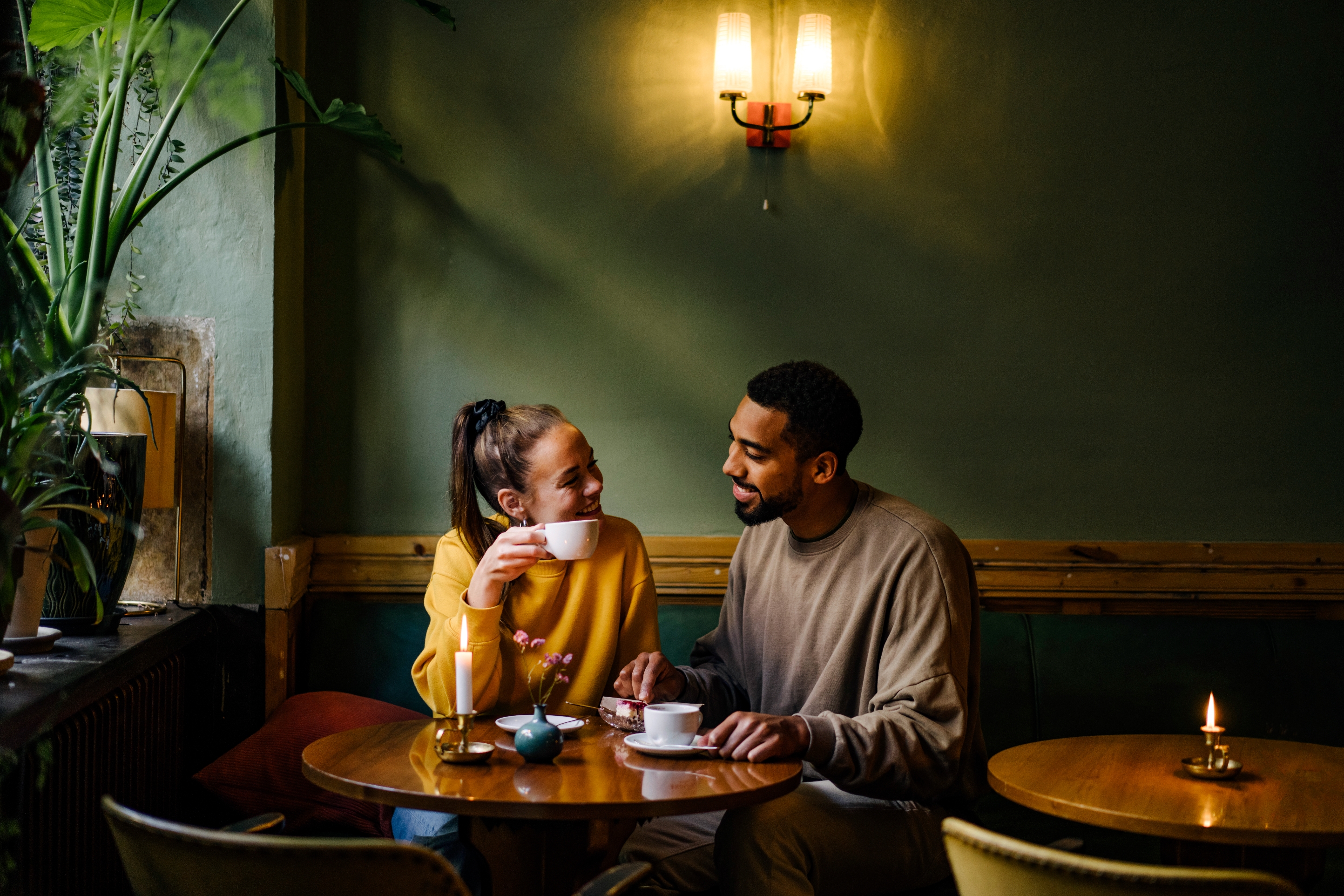 A couple enjoys a cozy coffee date, smiling and conversing at a small café table, creating an intimate and warm atmosphere