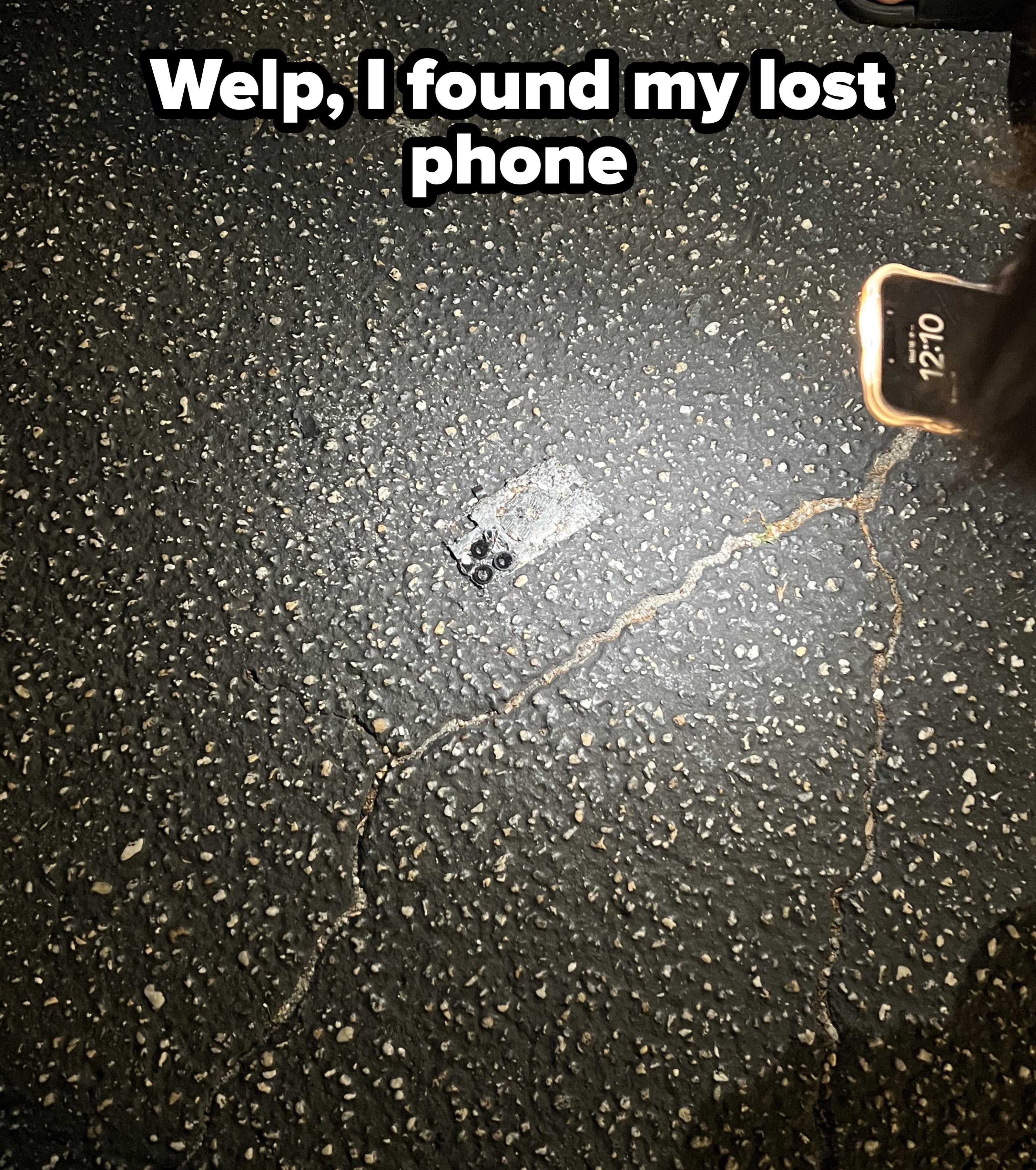 Smartphone on cracked asphalt illuminated by flashlight