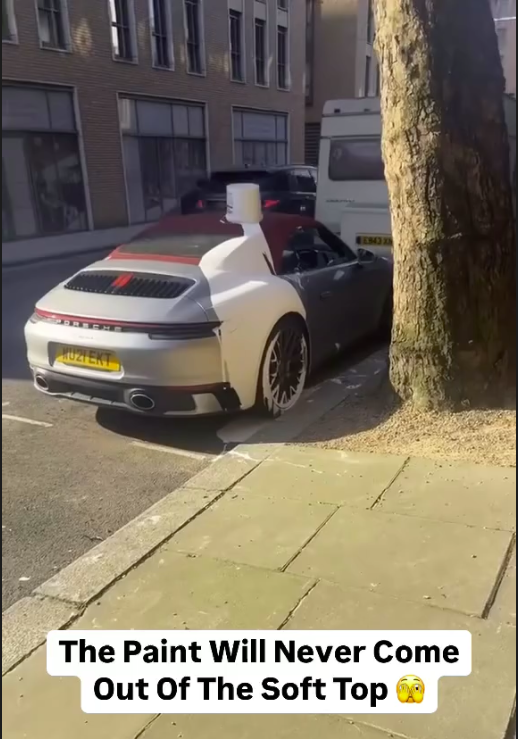A sports car with white paint spilled over its convertible roof is parked on a street. Text: "The Paint Will Never Come Out Of The Soft Top."