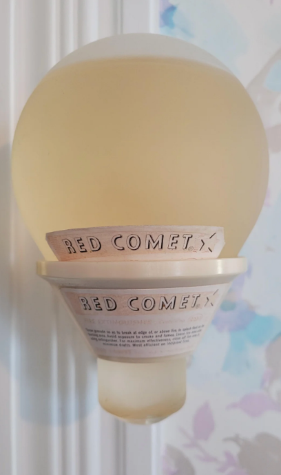 Spherical object that looks like a light bulb with liquid inside labeled "Red Comet" on a wall mount