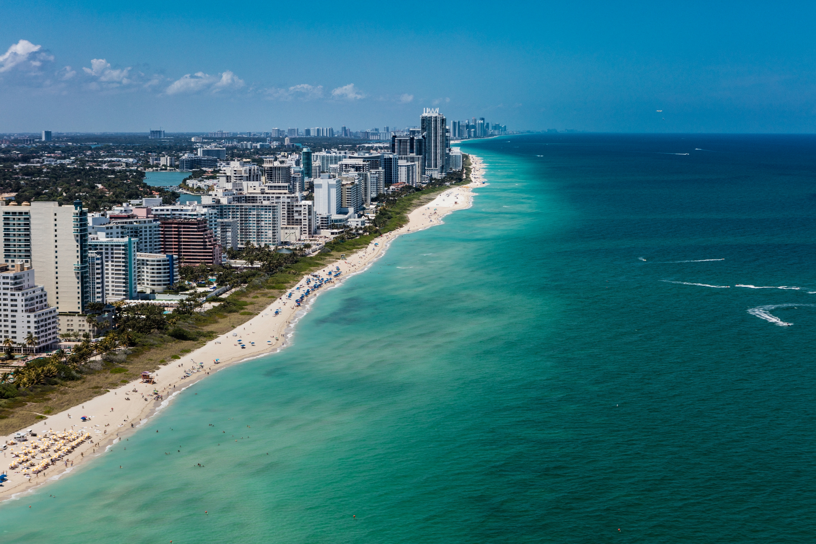 Aerial view of a city skyline along a coastline with busy beaches and dense high-rise buildings, illustrating urban coastal development