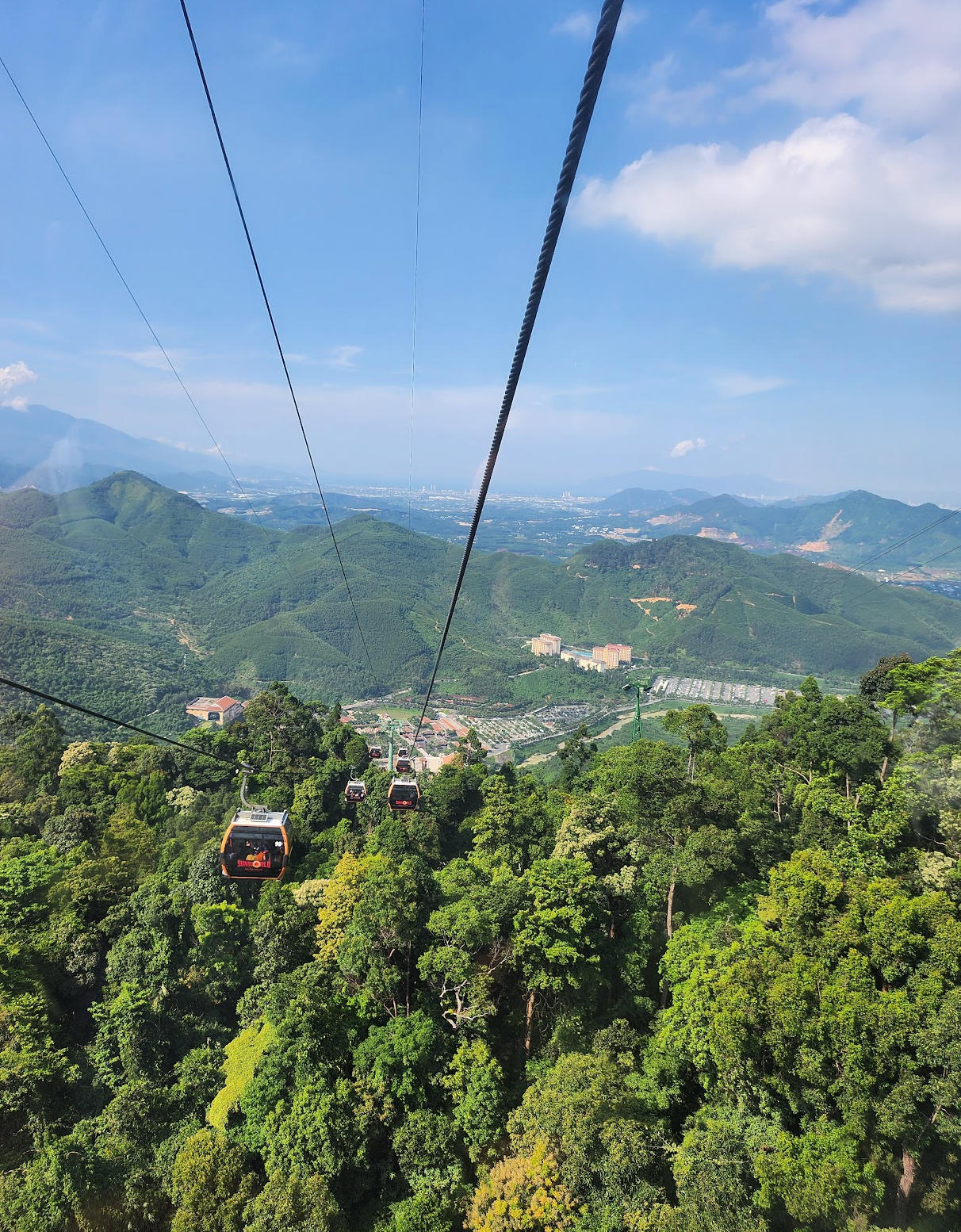 Cable cars travel over lush, green mountainous landscape, providing expansive views of hills and valleys below