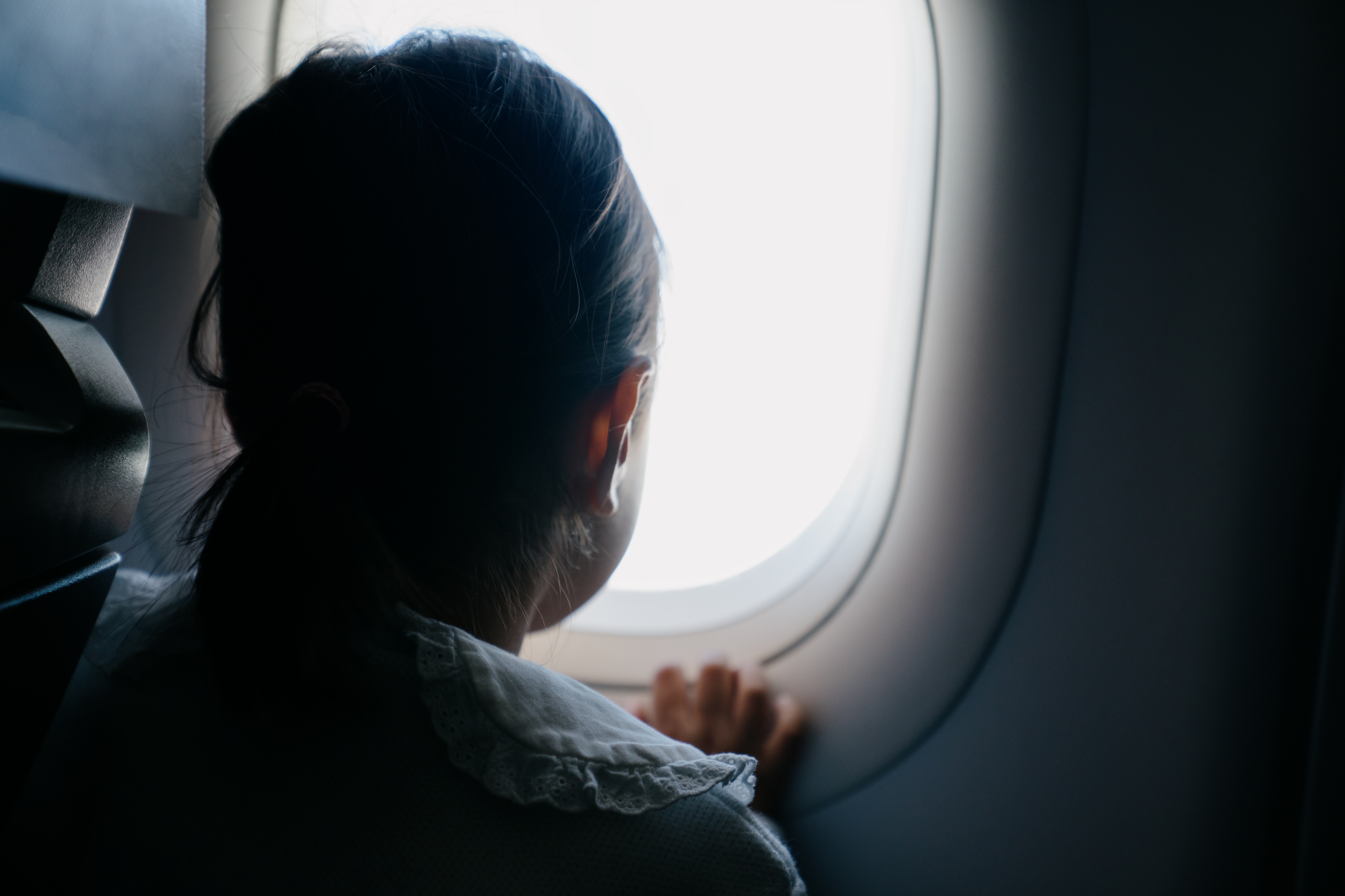 Person looking out airplane window, gazing at the sky during flight