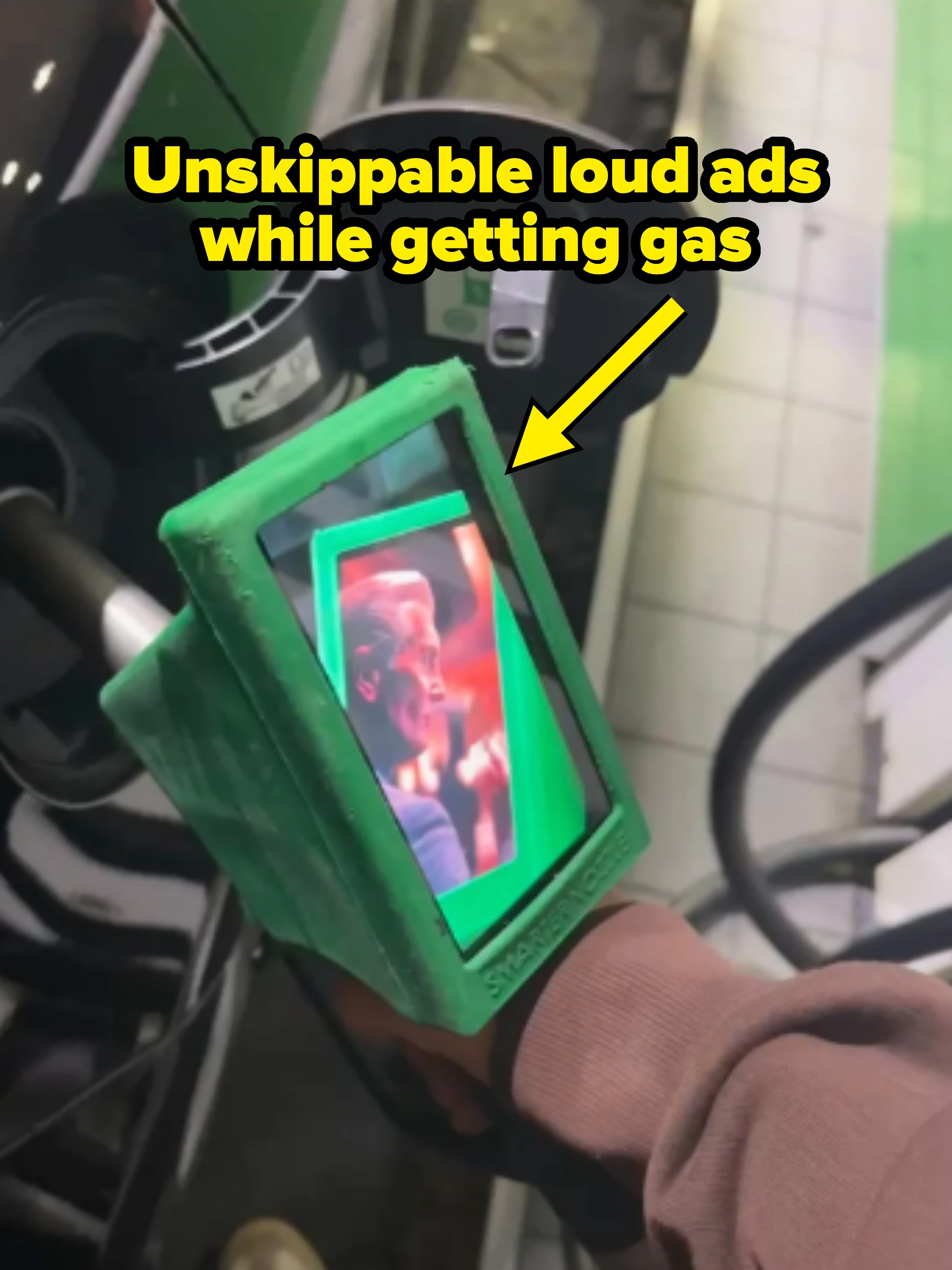 Gas pump with a small screen playing an , visible while a person is fueling their vehicle