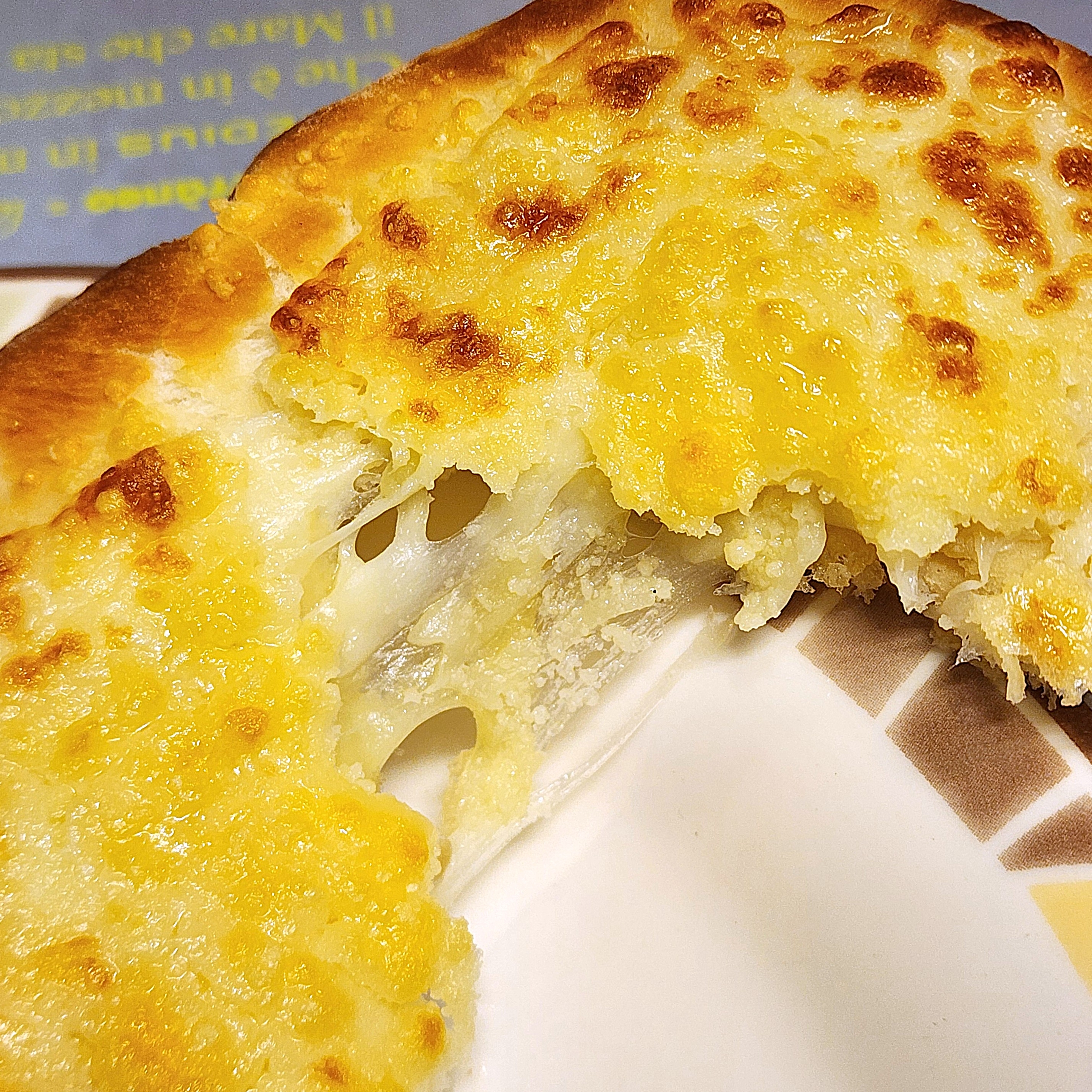 チーズがたっぷり乗ったピザの一片がクローズアップされています。とろけるチーズが見えて食欲をそそります。