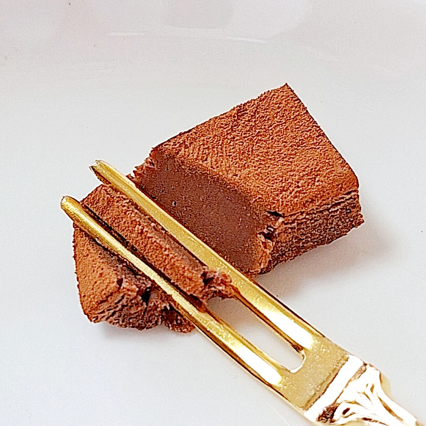 フォークに刺さった濃厚なチョコレートケーキの一切れ。