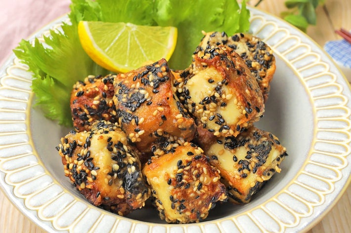 ゴマがまぶされた揚げ豆腐がレタスとレモンスライスと共に皿に盛られている。