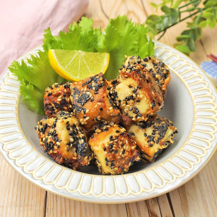 ゴマがまぶされた揚げ豆腐がレタスとレモンスライスと共に皿に盛られている。