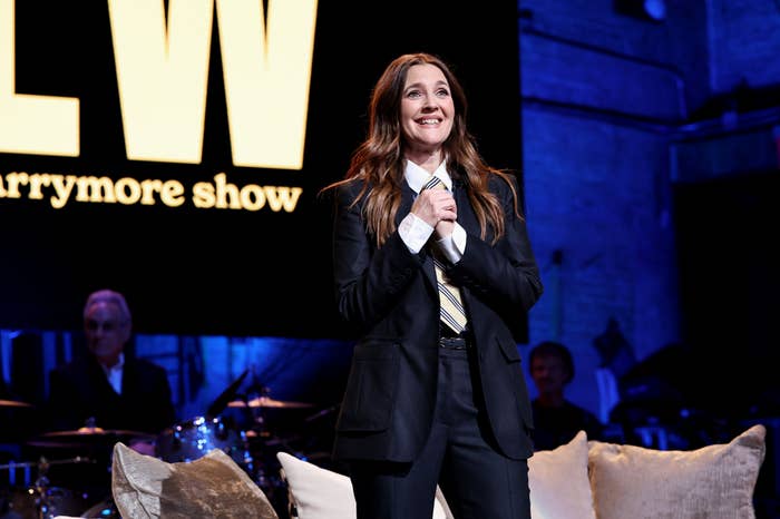 A person in a black suit and tie is smiling on stage with 
