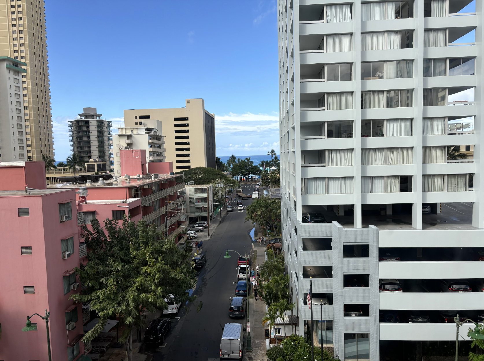 Street view from a high floor overlooking city buildings and a distant ocean