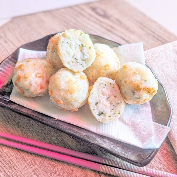 皿に盛られたタコ焼きが紙ナプキンの上にのっている。隣にはピンクの箸が添えられている。