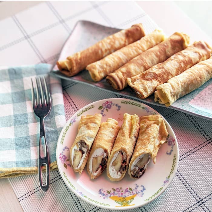 皿に盛られたクレープ。中身はバナナやクリーム。フォークと布ナプキンが添えられ、シンプルなテーブルセッティング。