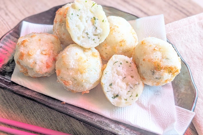 皿の上にタコ焼きが数個乗っている。中身が見えるように半分に切られたものもある。イメージは広告用。