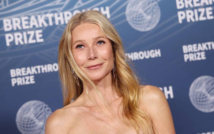 A person in elegant attire poses at the Breakthrough Prize event backdrop