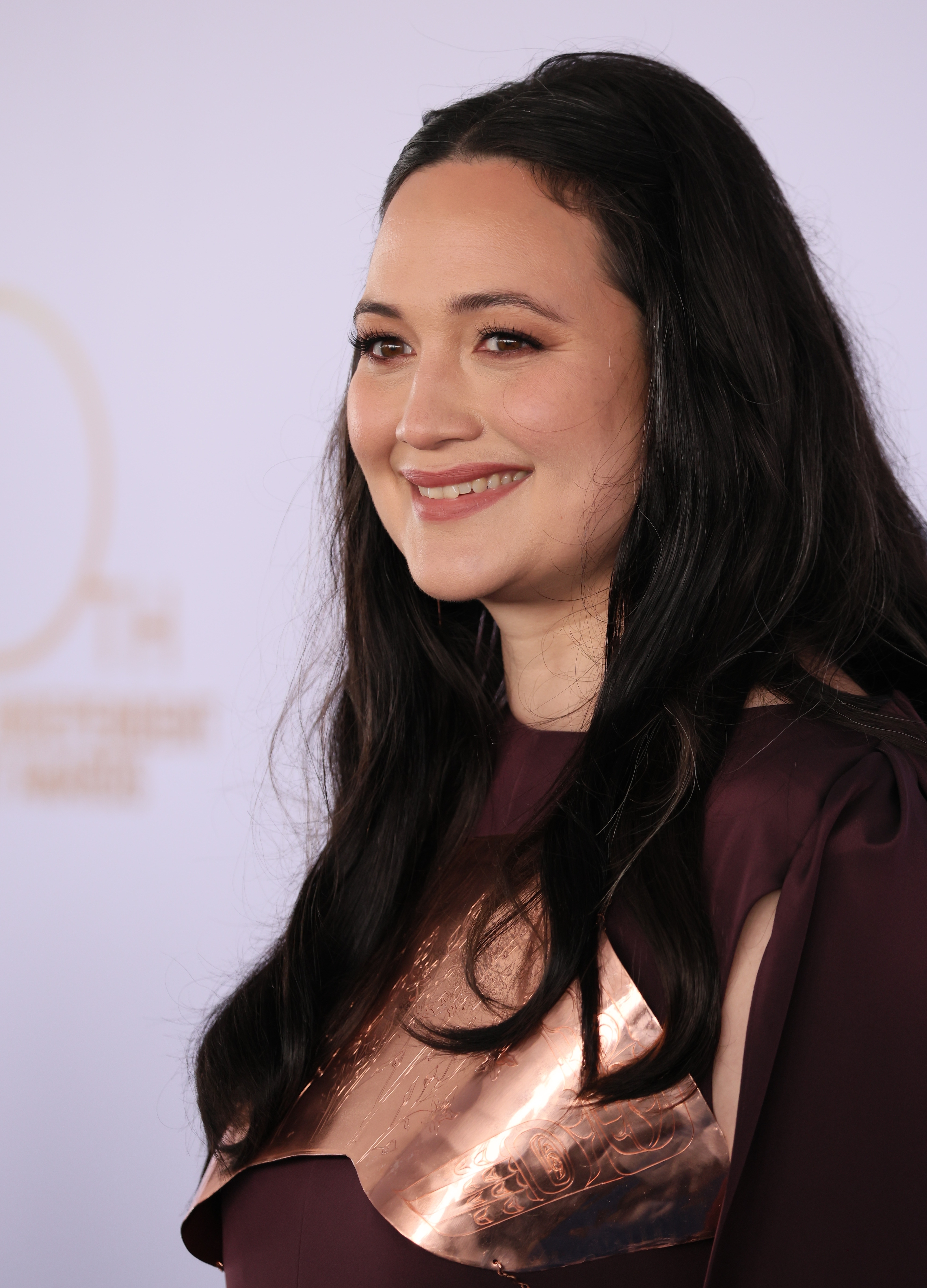 Lily Gladstone in elegant outfit with metallic accents, smiling at an event