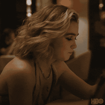 Person sitting at a table in a restaurant, appearing contemplative with a slight frown, while looking down