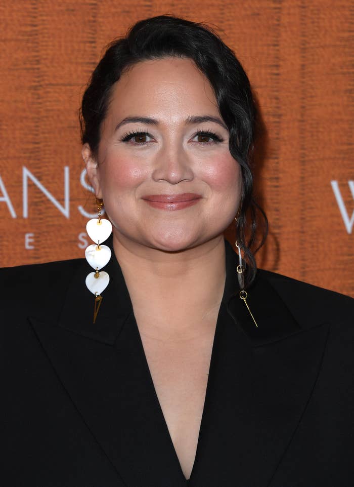 Lily Gladstone wearing statement earrings and a black jacket, smiling at an event