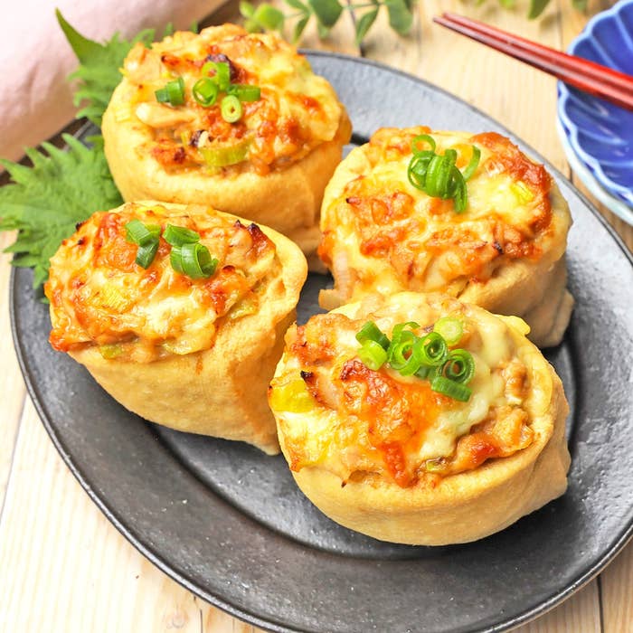 和風の揚げ豆腐の上にチーズと刻みネギが乗った料理が4つ、黒い皿に盛られています。