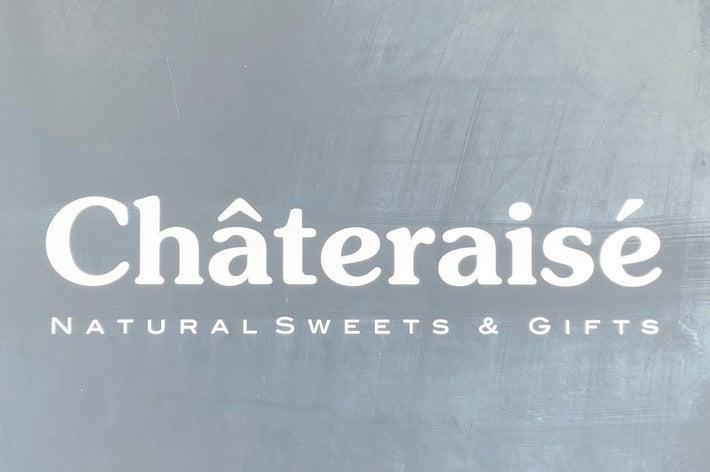 薄暗い背景に「Châteraisé NATURAL SWEETS &amp; GIFTS」と書かれた看板が表示されている。