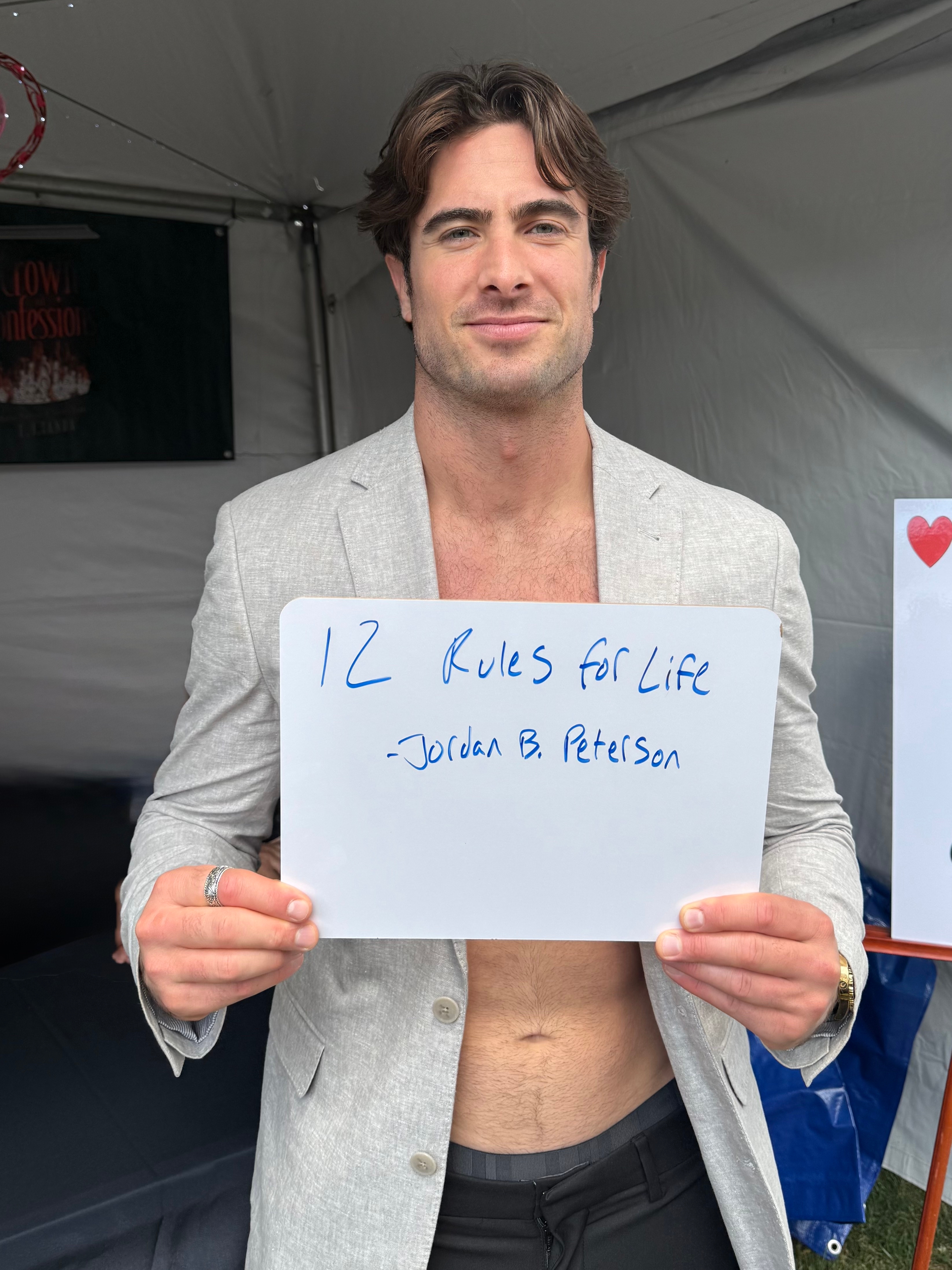 A person holding a sign with the text "12 Rules for Life - Jordan B. Peterson."