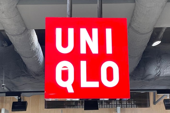 Uniqlo store interior with a red sign displaying the brand&rsquo;s name, visible clothing shelves, and price tags