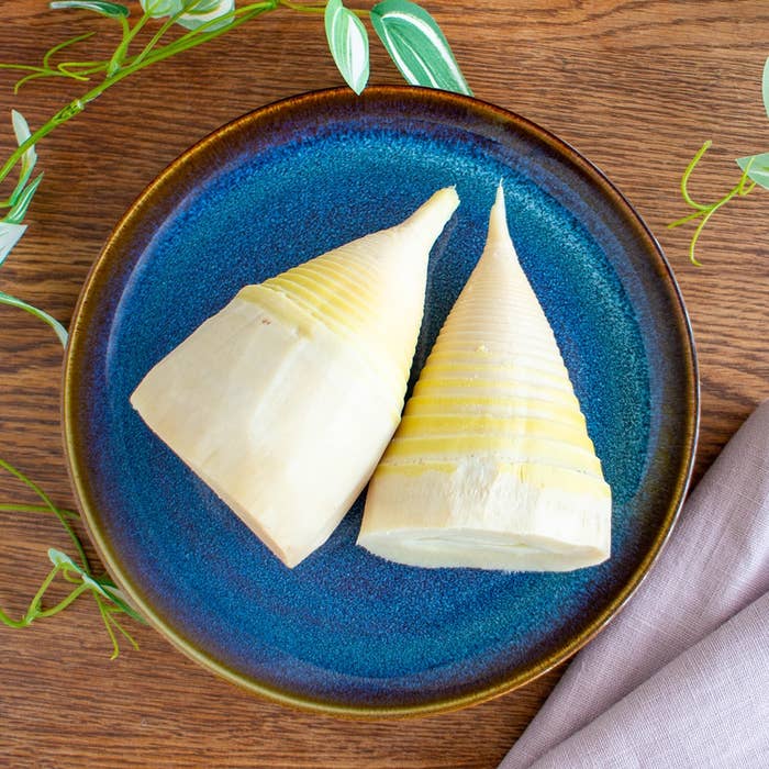 青い皿に盛られた2つのたけのこがテーブルに置かれている。