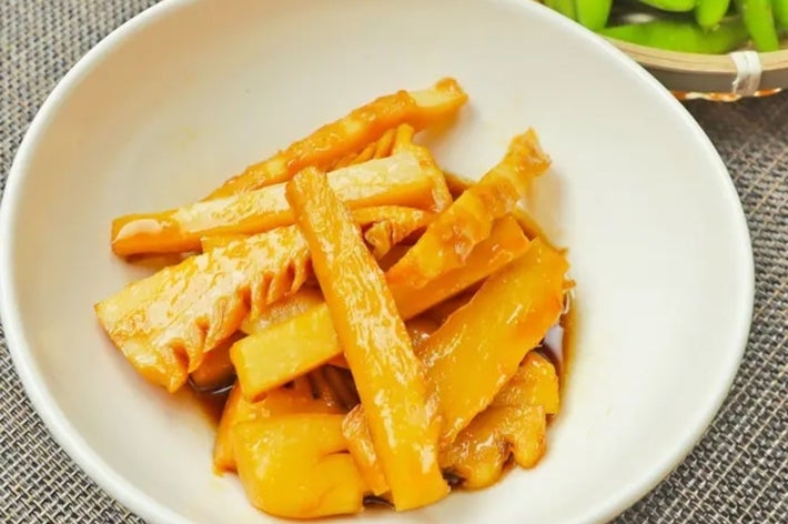 白い皿に盛られたタケノコの煮物と横に枝豆が置かれたビールグラス。