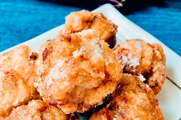 皿に盛られた揚げた食べ物のクローズアップ。背景にナスが見える。