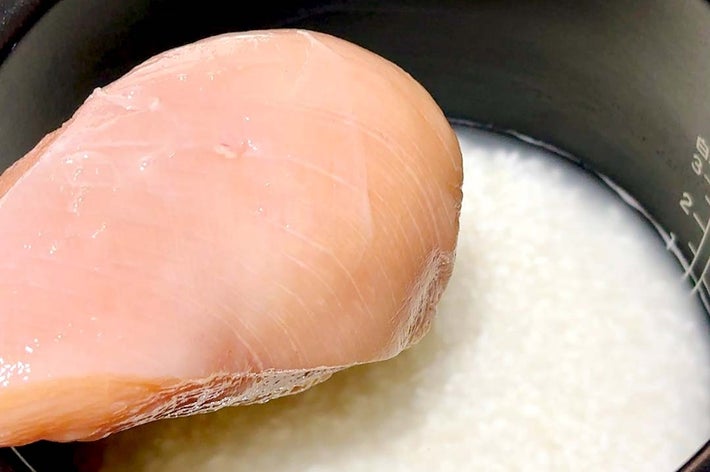 炊飯器に入れられた鶏むね肉と液体。