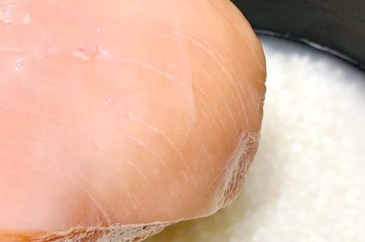 炊飯器に入れられた鶏むね肉と液体。