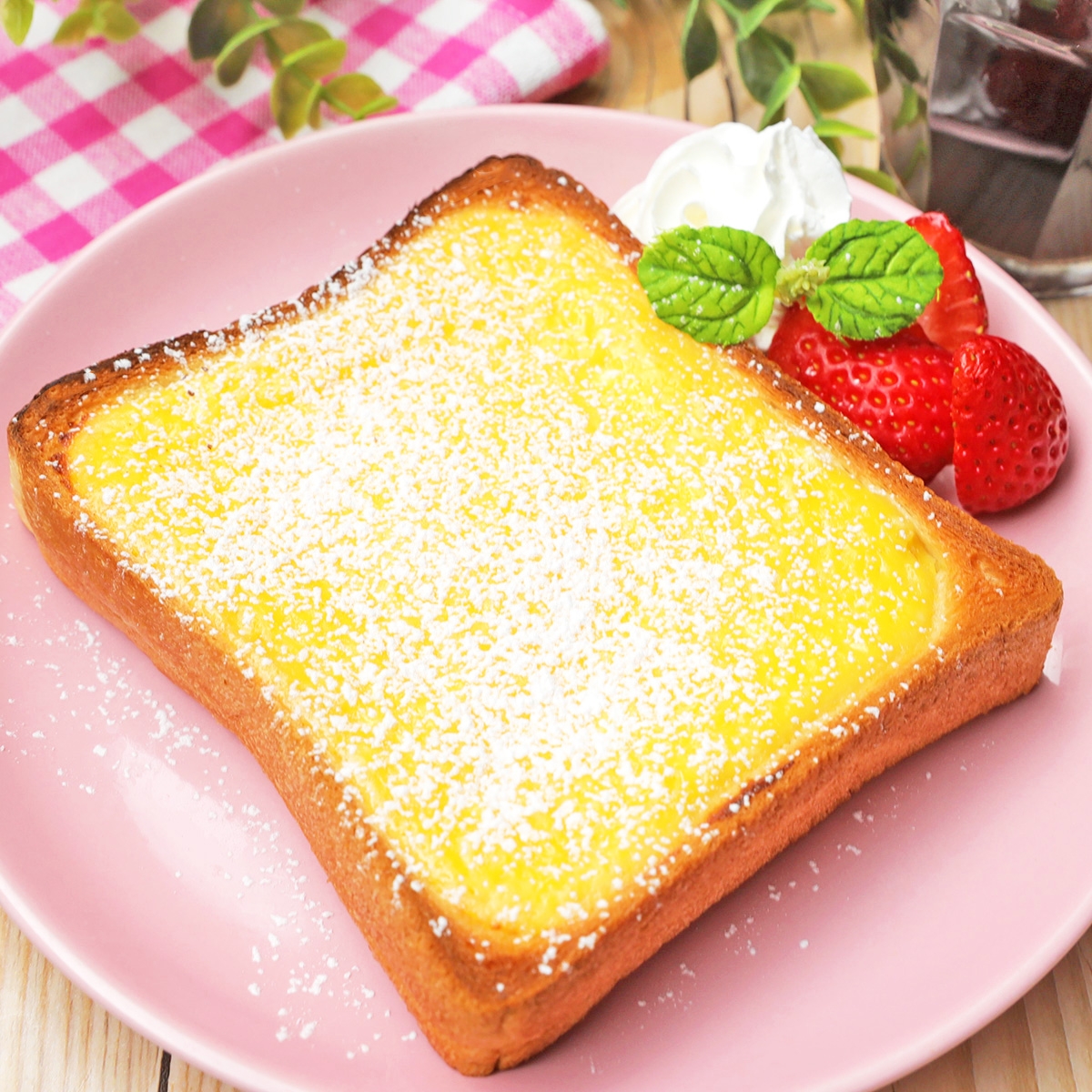 パンにクリームと粉砂糖がかかったデザート。イチゴとクリームで飾られています。