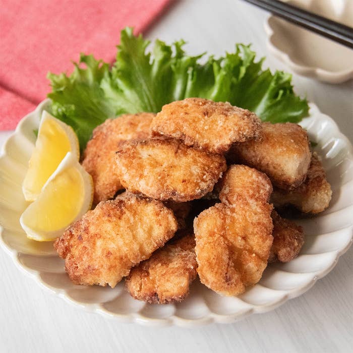 皿に盛られたフライドチキンとレモンのくし切り、背景にレタス。