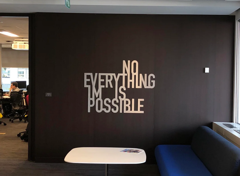 Creative wall installation in an office setting reads "NOTHING IS IMPOSSIBLE" with "NO" highlighted, forming "EVERYTHING IS POSSIBLE."
