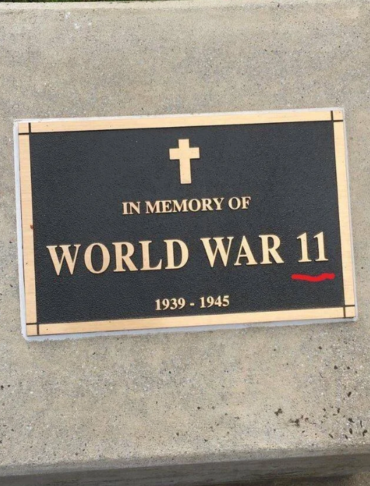 Plaque with a cross reads: "In Memory of World War 11, 1939-1945." "11" is underlined in red, indicating a humorous typo