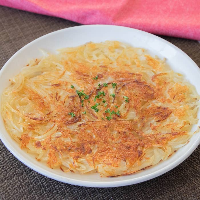 皿に盛られたカリッと焼かれたじゃがいもと玉ねぎのガレット。パセリが少量トッピングされています。